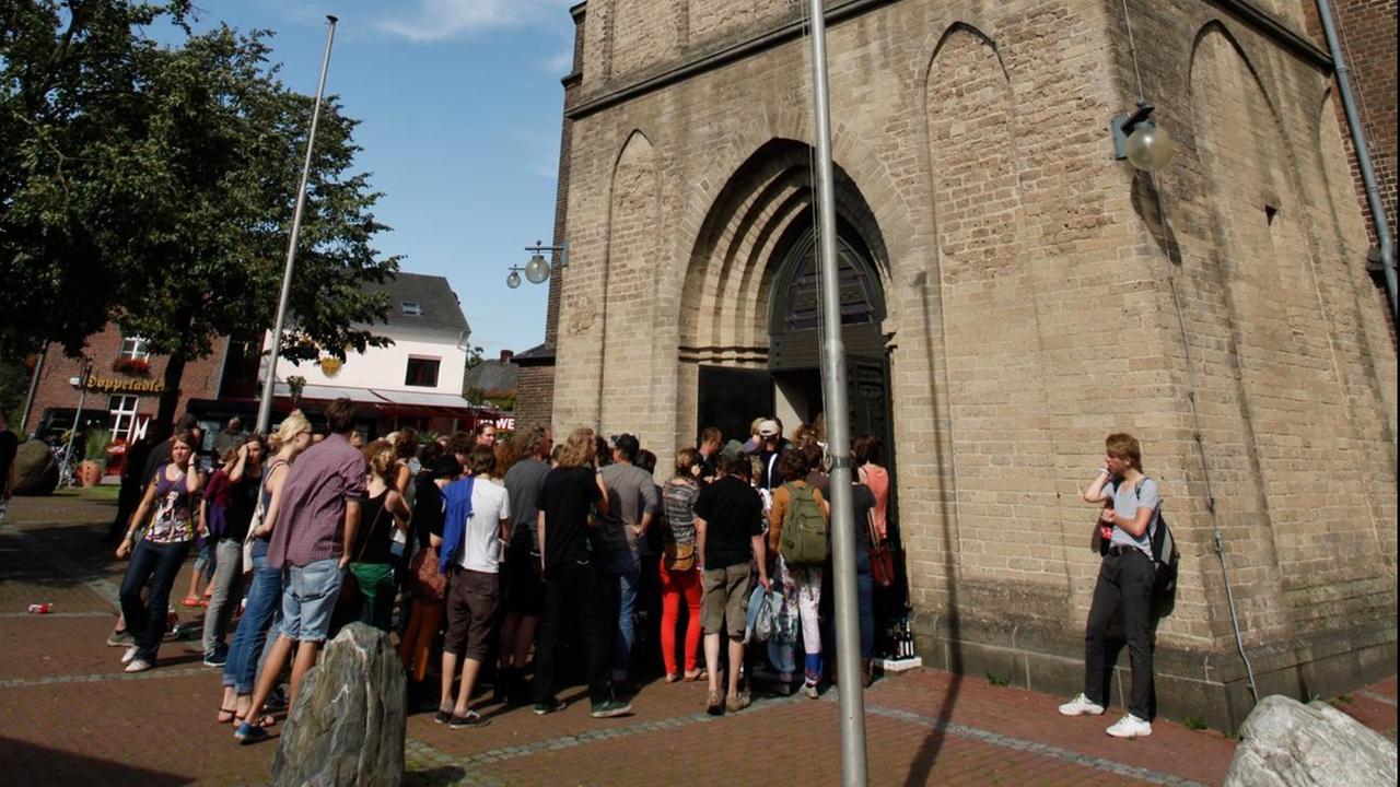 Besucher stehen Schlange vor der Ortskirche beim Haldern Pop Festival