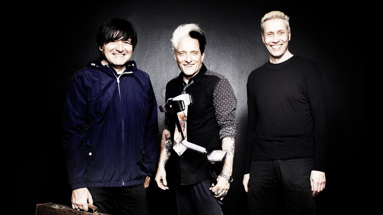 Porträtaufnahme der Band „Die Ärzte”, vor schwarzem Hintergrund. Porträtaufnahme der Band „Die Ärzte”, vor schwarzem Hintergrund.