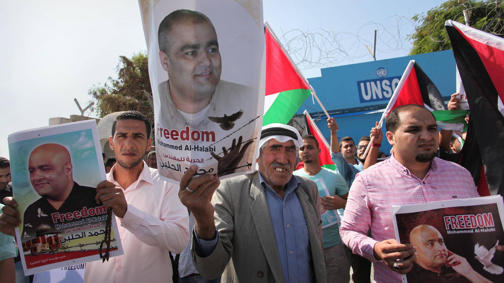 Palästinenser halten bei einer Solidaritätskundgebung für den verhafteten Direktor der US-Hilfsorganisation World Vision für den Gaza-Streifen, Mohammed el Halabi, vor dem Unesco-Sitz in Gaza (Stadt) am 16.10.2016 Fotos des Verhafteten in die Höhe. Palästinenser halten bei einer Solidaritätskundgebung für den verhafteten Direktor der US-Hilfsorganisation World Vision für den Gaza-Streifen, Mohammed el Halabi, vor dem Unesco-Sitz in Gaza (Stadt) am 16.10.2016 Fotos des Verhafteten in die Höhe.