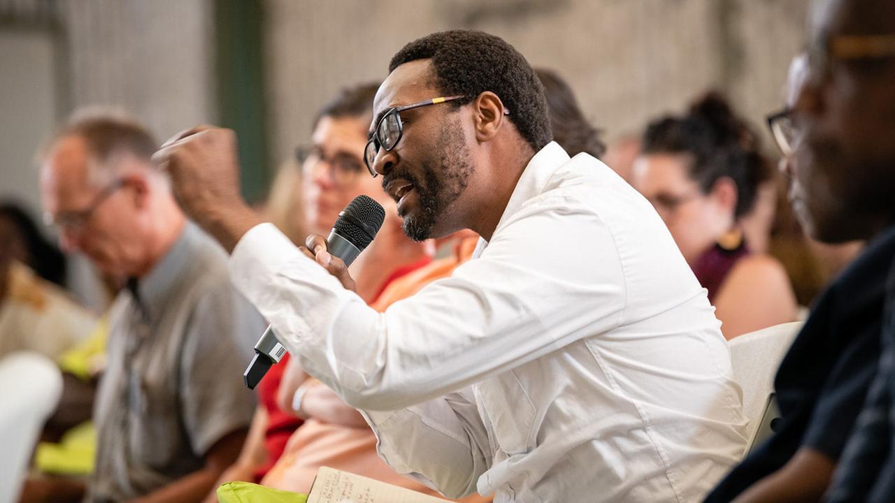 Wandile Kasibe, Koordinator der öffentlichen Programme der Iziko-Museen, diskutiert mit einem Mikrophon in der hand. Wandile Kasibe, Koordinator der öffentlichen Programme der Iziko-Museen, diskutiert mit einem Mikrophon in der hand.