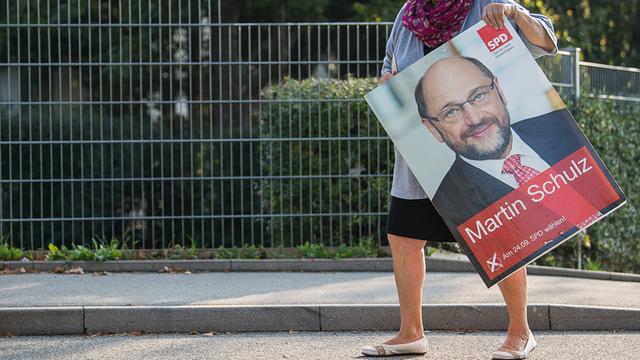 Eine Frau trägt am Tag nach der Bundestagswahl ein SPD-Wahlplakat mit Spitzenkandidat Schulz zu ihrem Auto