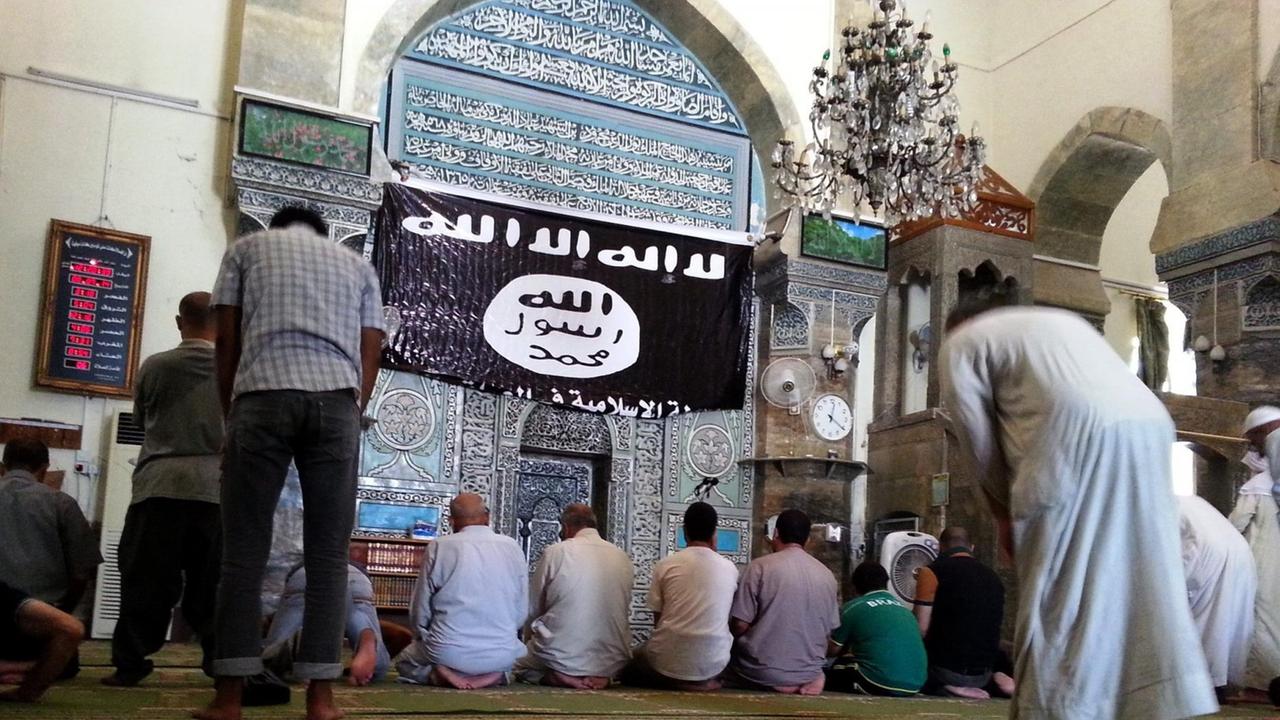 Gläubige beten in der Al-Noori Al-Kabir-Moschee, neben Flagge des sogenannten Islamischen Staates (IS)