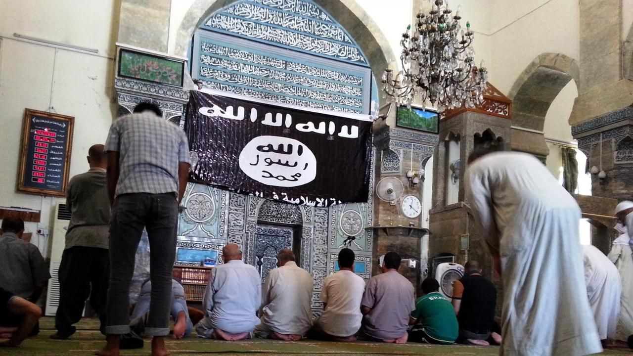 Gläubige beten in der Al-Noori Al-Kabir-Moschee, neben Flagge des sogenannten Islamischen Staates (IS) Gläubige beten in der Al-Noori Al-Kabir-Moschee, neben Flagge des sogenannten Islamischen Staates (IS)