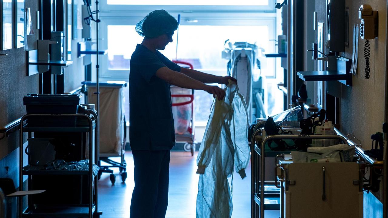 Eine Krankenschwester legt auf der Isolierstation für Coronavirus-Behandlungen ihre Schutzkleidung an bevor sie ein Patientenzimmer betritt. Eine Krankenschwester legt auf der Isolierstation für Coronavirus-Behandlungen ihre Schutzkleidung an bevor sie ein Patientenzimmer betritt.