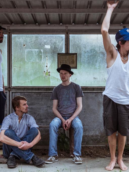 Die Mitglieder der Band "Kofelgschroa" stehen und hocken in einer alten Bushaltestelle