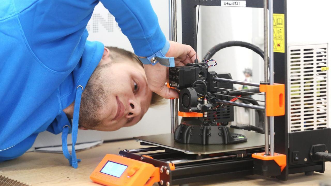 Fachkraft justiert einen 3-D Drucker 