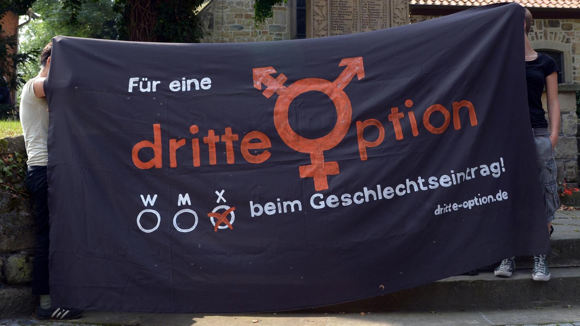 Zwei Personen halten ein Banner, auf dem steht: "Für eine dritte Option beim Geschlechtseintrag" Zwei Personen halten ein Banner, auf dem steht: "Für eine dritte Option beim Geschlechtseintrag"