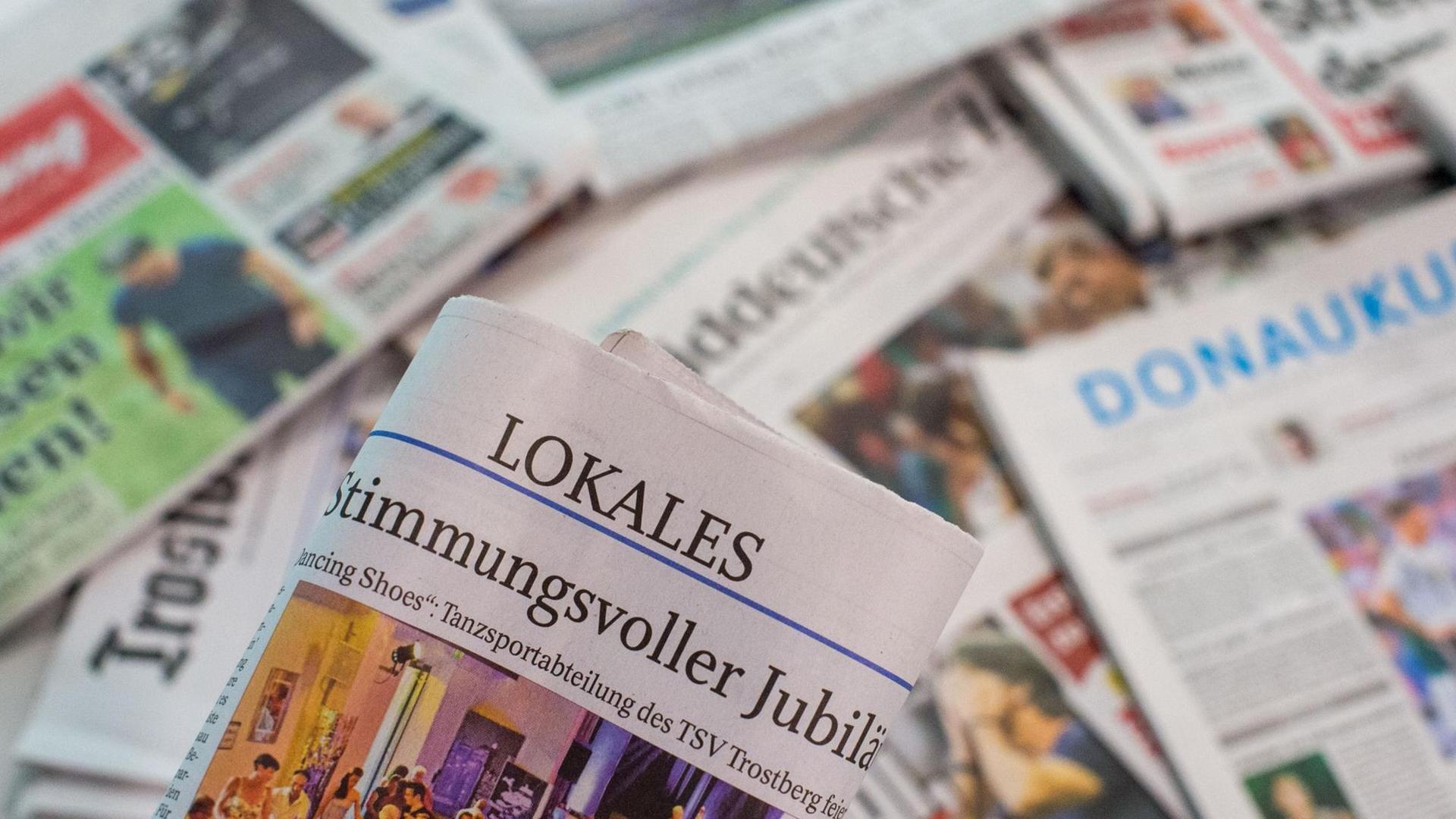 Eine Lokalzeitung wird über andere Zeitungen gehalten. Eine Lokalzeitung wird über andere Zeitungen gehalten.