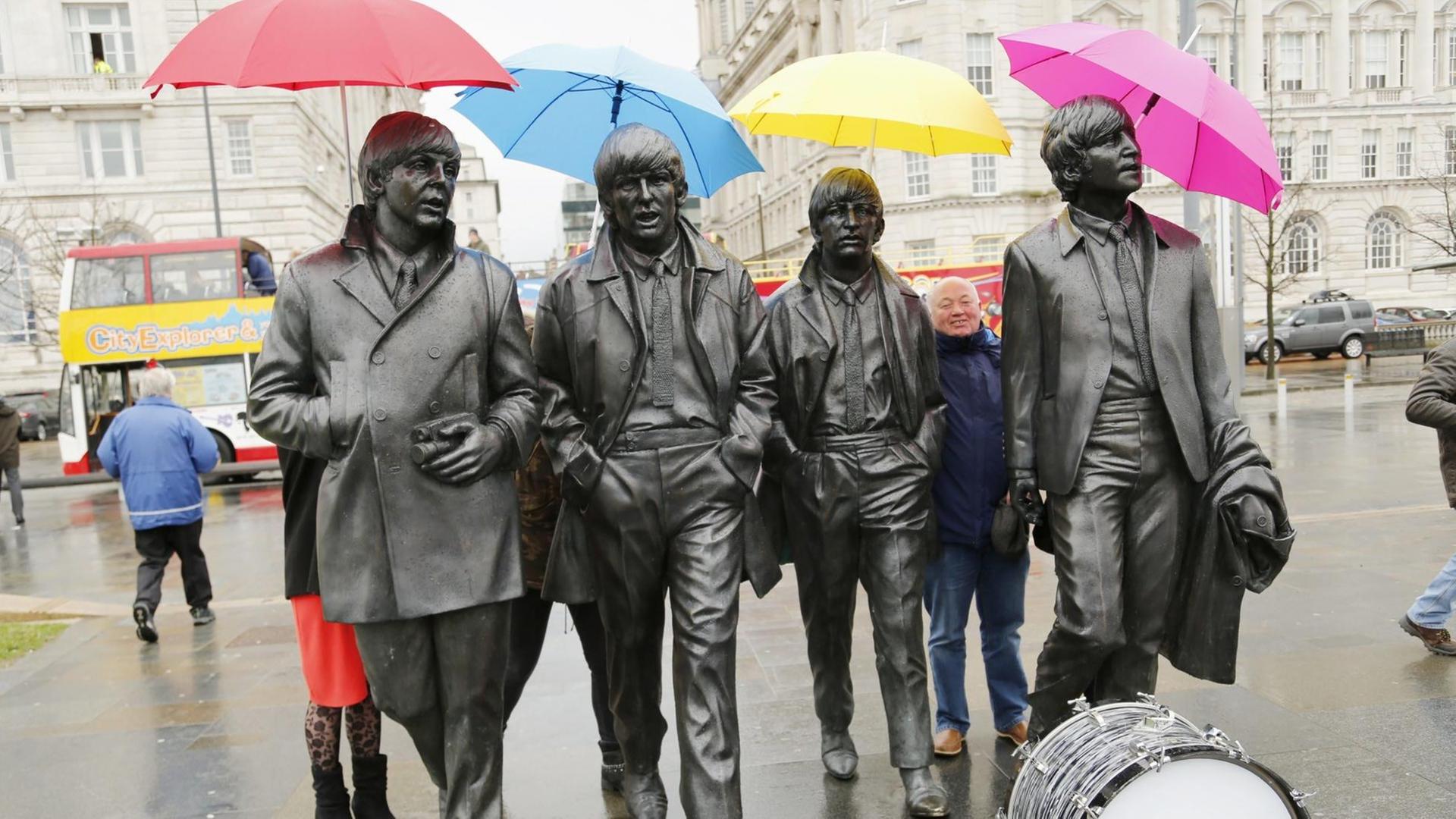 Liverpool feiert den 50. Geburtstag des Beatles Albums "Sgt. Pepper's Lonely Hearts Club Band". Menschen halten bunte Regenschirme über die Köpfe eines Denkmals zuehren der Gruppe. Liverpool feiert den 50. Geburtstag des Beatles Albums "Sgt. Pepper's Lonely Hearts Club Band". Menschen halten bunte Regenschirme über die Köpfe eines Denkmals zuehren der Gruppe.
