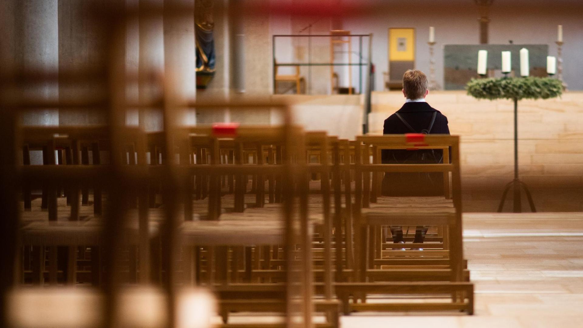 Eine Frau sitzt alleine im Hildesheimer Dom. Eine Frau sitzt alleine im Hildesheimer Dom.