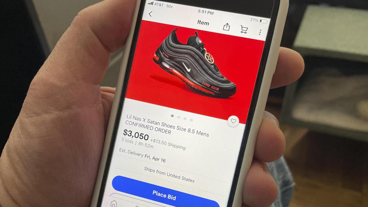 Eine Hand hält ein Smartphone. Auf dem Display sind schwarze Sneaker zu sehen, für die bei Ebay geboten wird. Eine Hand hält ein Smartphone. Auf dem Display sind schwarze Sneaker zu sehen, für die bei Ebay geboten wird.