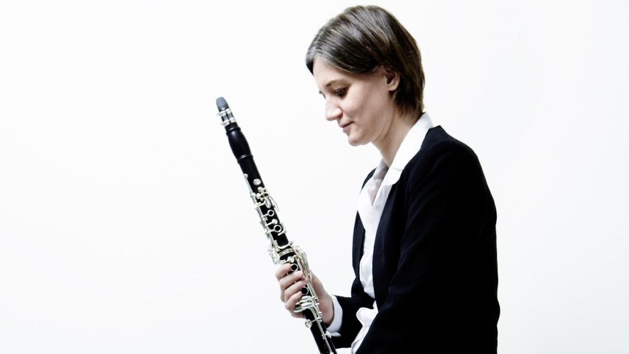 Die Schweizer Klarinettistin Rita Karin Meier im Halbporträt und in Seitenansicht mit der Klarinette in der Hand.
