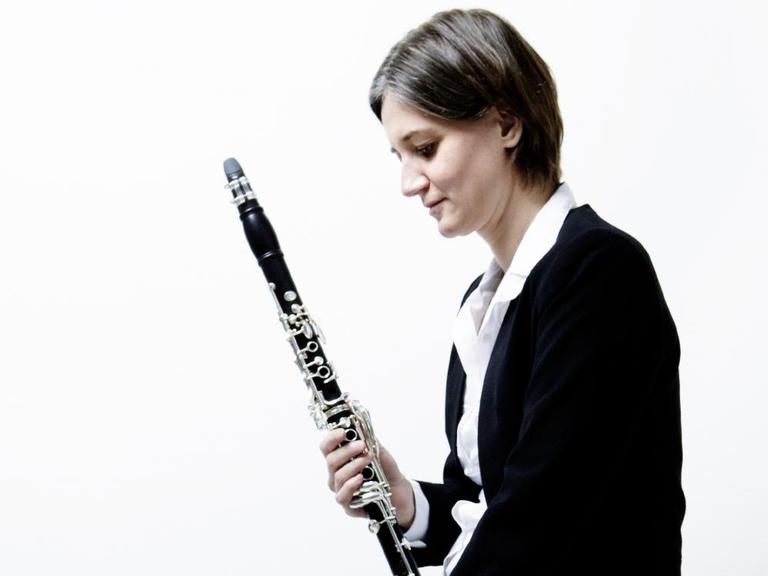 Die Schweizer Klarinettistin Rita Karin Meier im Halbporträt und in Seitenansicht mit der Klarinette in der Hand.