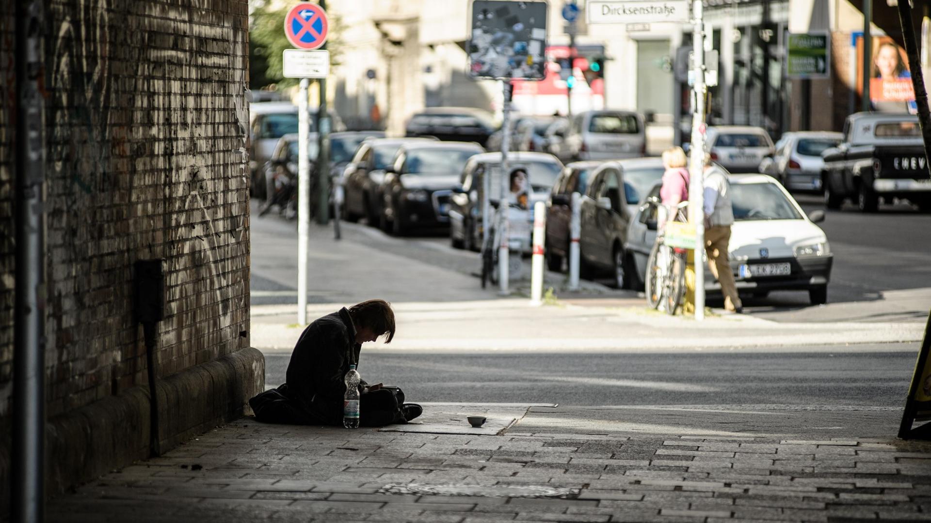Ein Mann sitzt in einer Unterführung vor einem Schälchen auf dem Gehweg. Ein Mann sitzt in einer Unterführung vor einem Schälchen auf dem Gehweg.