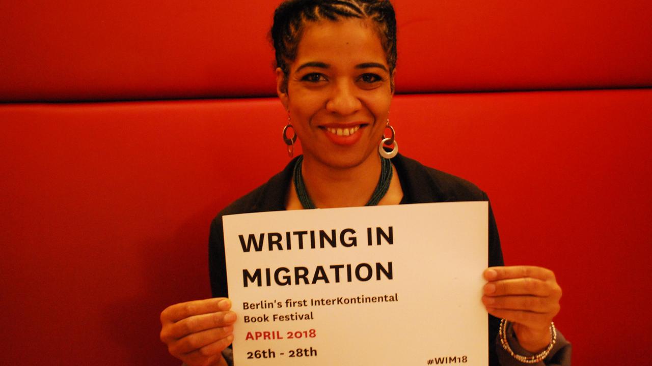 Olumide Popoola, die Kuratorin von "Writing in Migration" hält ein Schild auf dem das Datum des Literaturfestivals zu sehen ist: 26.-28.4.2018 Olumide Popoola, die Kuratorin von "Writing in Migration" hält ein Schild auf dem das Datum des Literaturfestivals zu sehen ist: 26.-28.4.2018