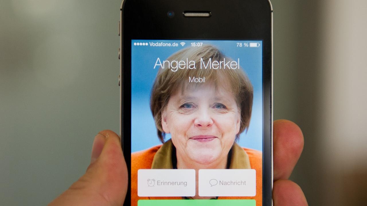 Ein Mann hält ein Apple iPhone 4S, auf dem der fiktive Kontakt Angela Merkel anruft und ein Bild der Bundeskanzlerin zu sehen ist. Ein Mann hält ein Apple iPhone 4S, auf dem der fiktive Kontakt Angela Merkel anruft und ein Bild der Bundeskanzlerin zu sehen ist.