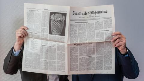Carsten Knop, Chefredakteur Digitale Produkte (l), und Berthold Kohler, Herausgeber der Frankfurter Allgemeinen Zeitung (FAZ, r), stehen in den Redaktionsräumen hinter einem Exemplar der ersten FAZ-Ausgabe vom 01.11.1949. Die Zeitung feiert ihr 70-jähriges Bestehen.