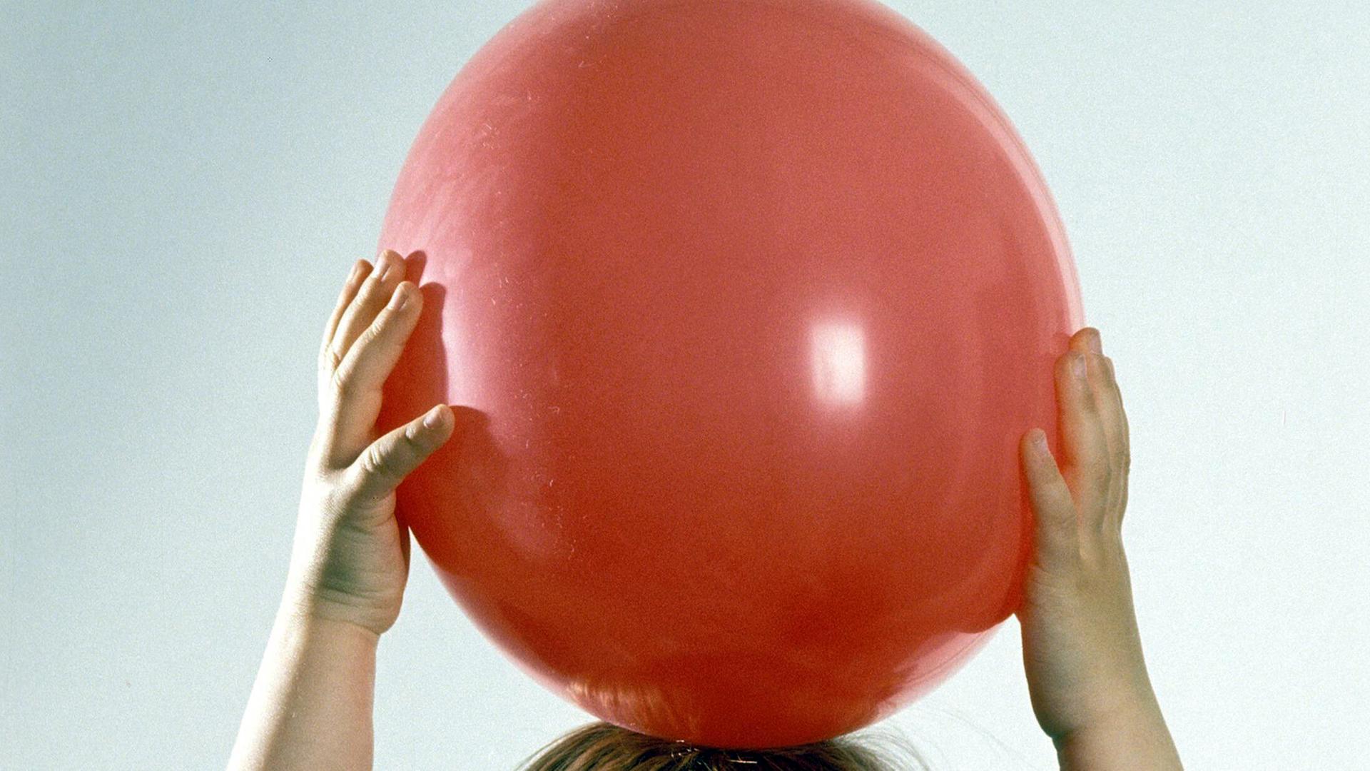 .Kinderhände halten einen roten Ball in die Luft. .Kinderhände halten einen roten Ball in die Luft.