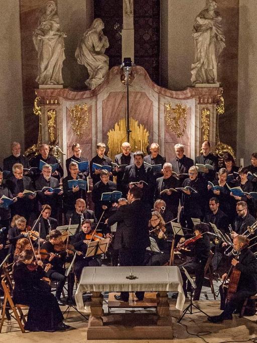 Das Bild zeigt den Chor mit Orchester bei einem Konzert vor dem Altar in der Kirche.