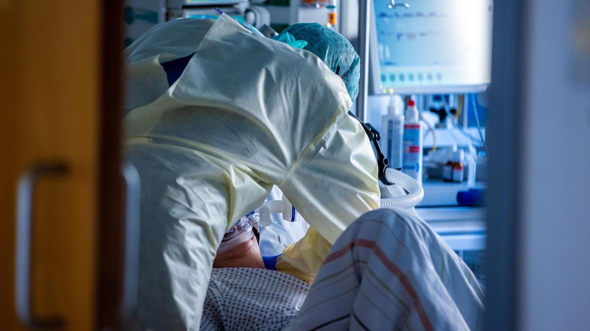 Ein Mitarbeiter richtet bei einer an Covid-19 erkrankten Patientin in einem Zimmer des besonders geschützten Teils der Intensivstation des Universitätsklinikums Greifswald die Beatmungsmaske. Ein Mitarbeiter richtet bei einer an Covid-19 erkrankten Patientin in einem Zimmer des besonders geschützten Teils der Intensivstation des Universitätsklinikums Greifswald die Beatmungsmaske.