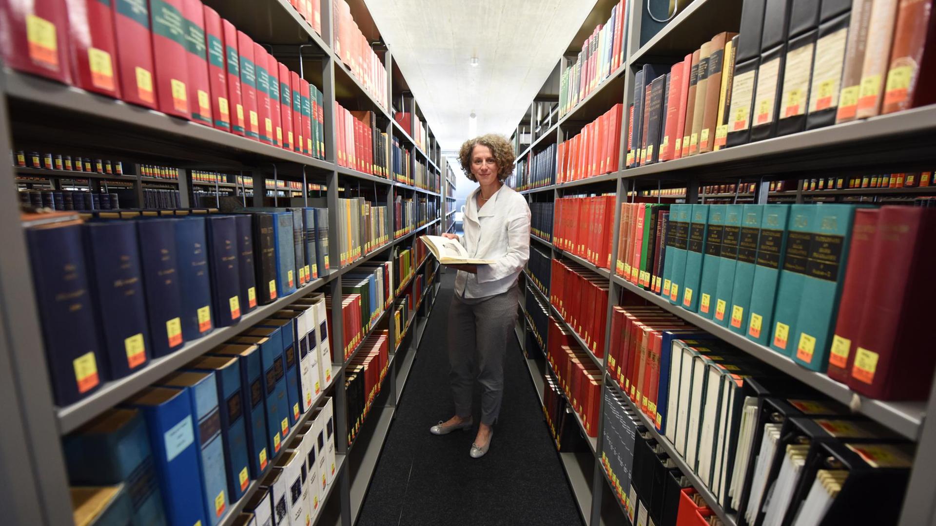 Bibliotheksdirektorin Antje Kellersohn posiert zwischen Bücherregalen in der Universitätsbibliothek