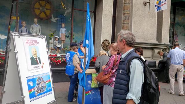 Auf einer Straße in Weißrussland sammeln Kandidaten Unterschriften vor den Präsidentschaftswahlen in Weißrussland: Jeder Bewerber braucht mindestens 100.000 Unterstützer. Auf einem Wahlplakat ist der amtierende Präsident Alexander Grigorjewitsch Lukaschenko abgebildet.