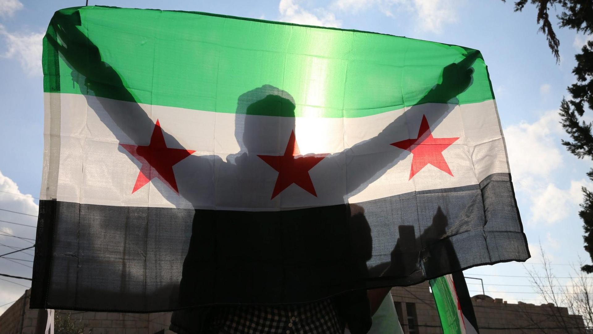 Während einer Demonstration in Jordanien gegen die russischen Luftangriffe auf Aleppo hält ein Syrer die Flagge seines Heimatlandes hoch. Während einer Demonstration in Jordanien gegen die russischen Luftangriffe auf Aleppo hält ein Syrer die Flagge seines Heimatlandes hoch.