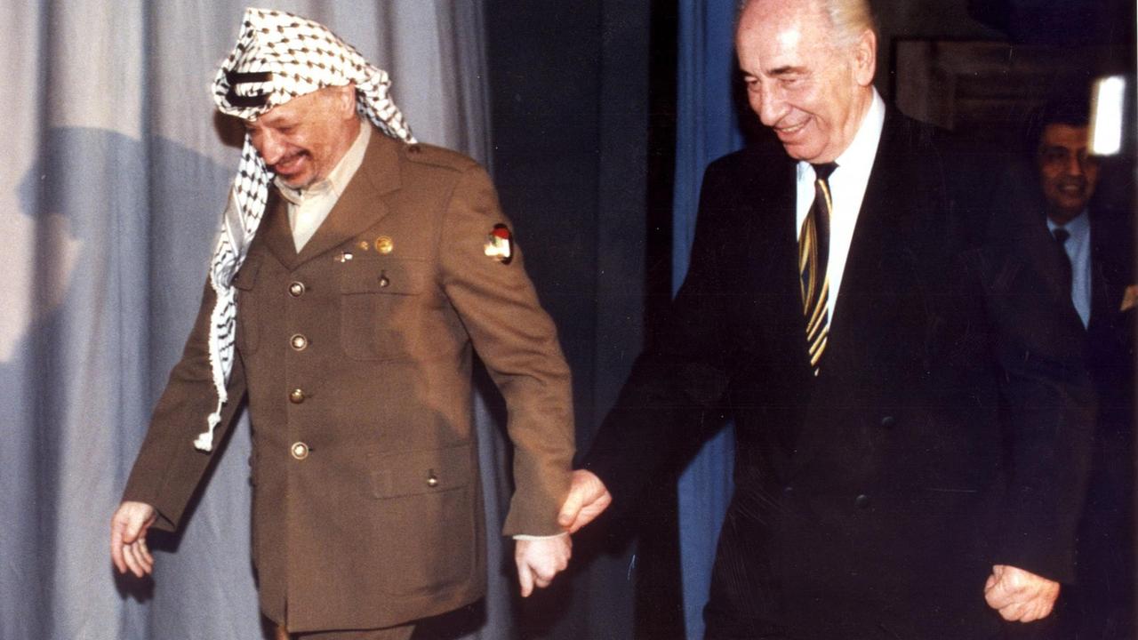 Shimon Peres und Yassir Arafat betreten Hand in Hand eine Bühne. Shimon Peres und Yassir Arafat betreten Hand in Hand eine Bühne.