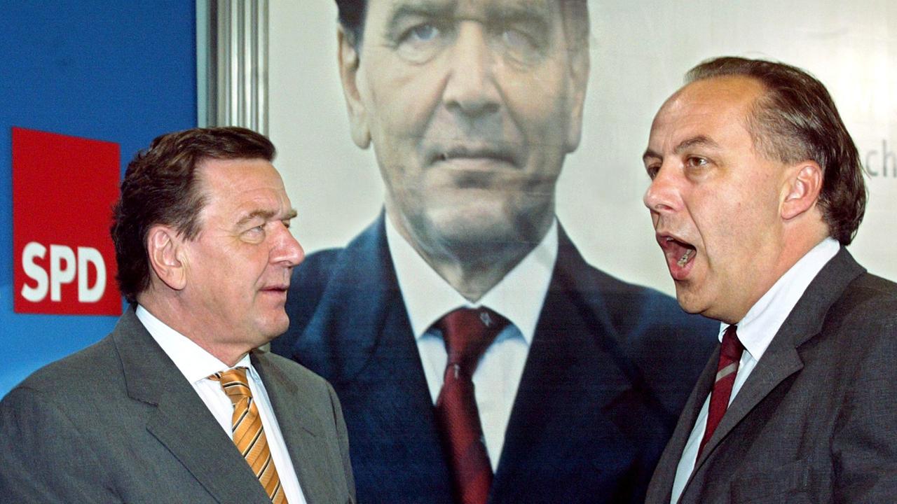 Bundeskanzler Gerhard Schröder (SPD) und der Bundesgeschäftsführer und Wahlkampfleiter der SPD, Matthias Machnig (r.), stehen neben einem Plakat für die Bundestagswahl, das Schröders Konterfei zeigt.
