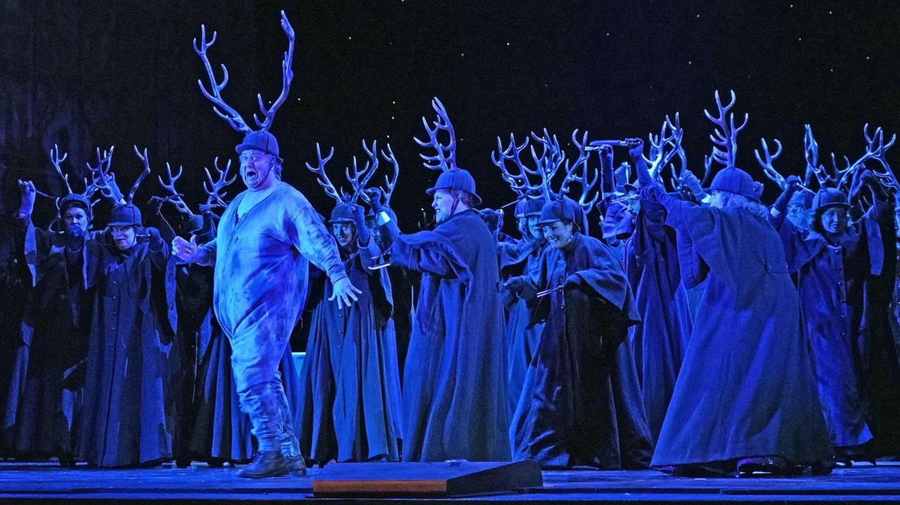 Falstaff mit Geweih wird von anderen dunklen Gestalten mit Hörnern umringt, die sich köstlich amüsieren. Falstaff mit Geweih wird von anderen dunklen Gestalten mit Hörnern umringt, die sich köstlich amüsieren.