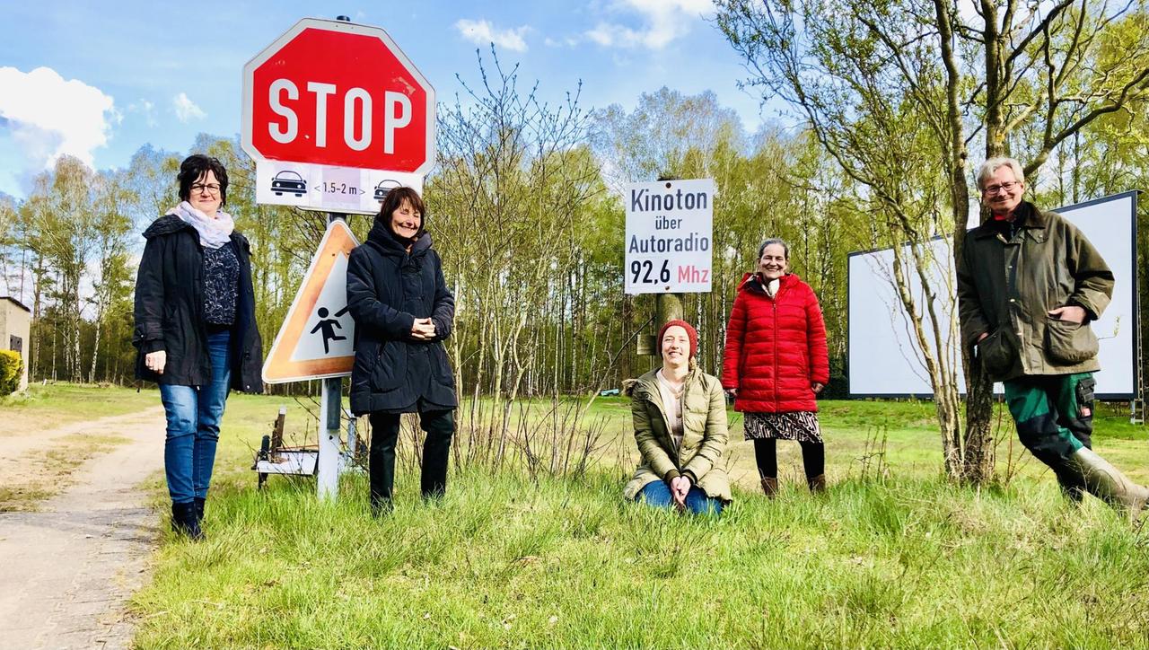 Fünf Menschen vor einem Schild im einer Wiesen- und Waldlandschaft. Auf einem Schild steht "Kinoton über Autoradio 92,6 Mhz" Fünf Menschen vor einem Schild im einer Wiesen- und Waldlandschaft. Auf einem Schild steht "Kinoton über Autoradio 92,6 Mhz"