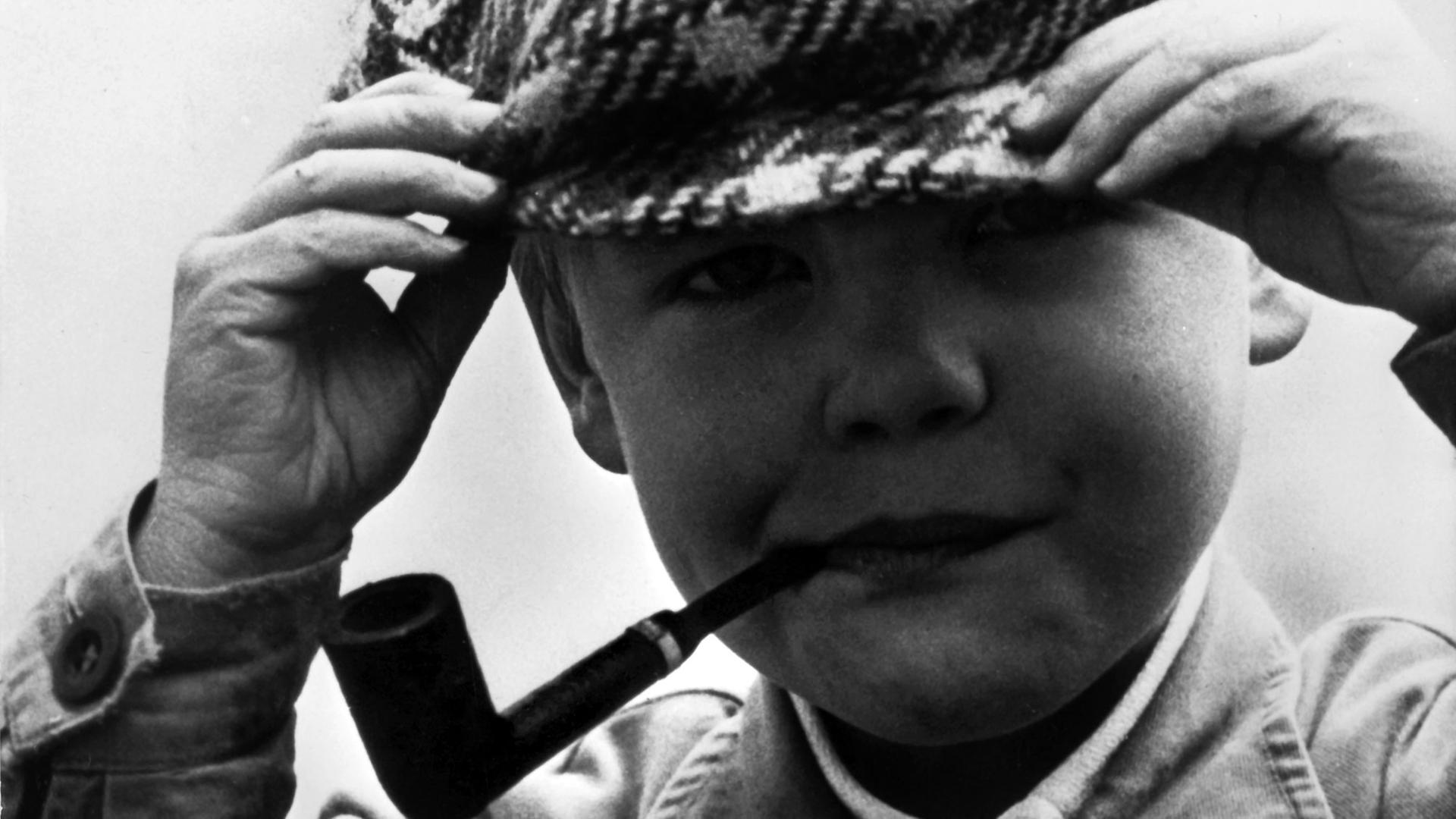 Ein kleiner Schweizer Junge hat sich mit Schirmmütze und Pfeife ausgerüstet und ist so als kleiner Meisterdetektiv wie sein Vorbild Sherlock Holmes unterwegs.