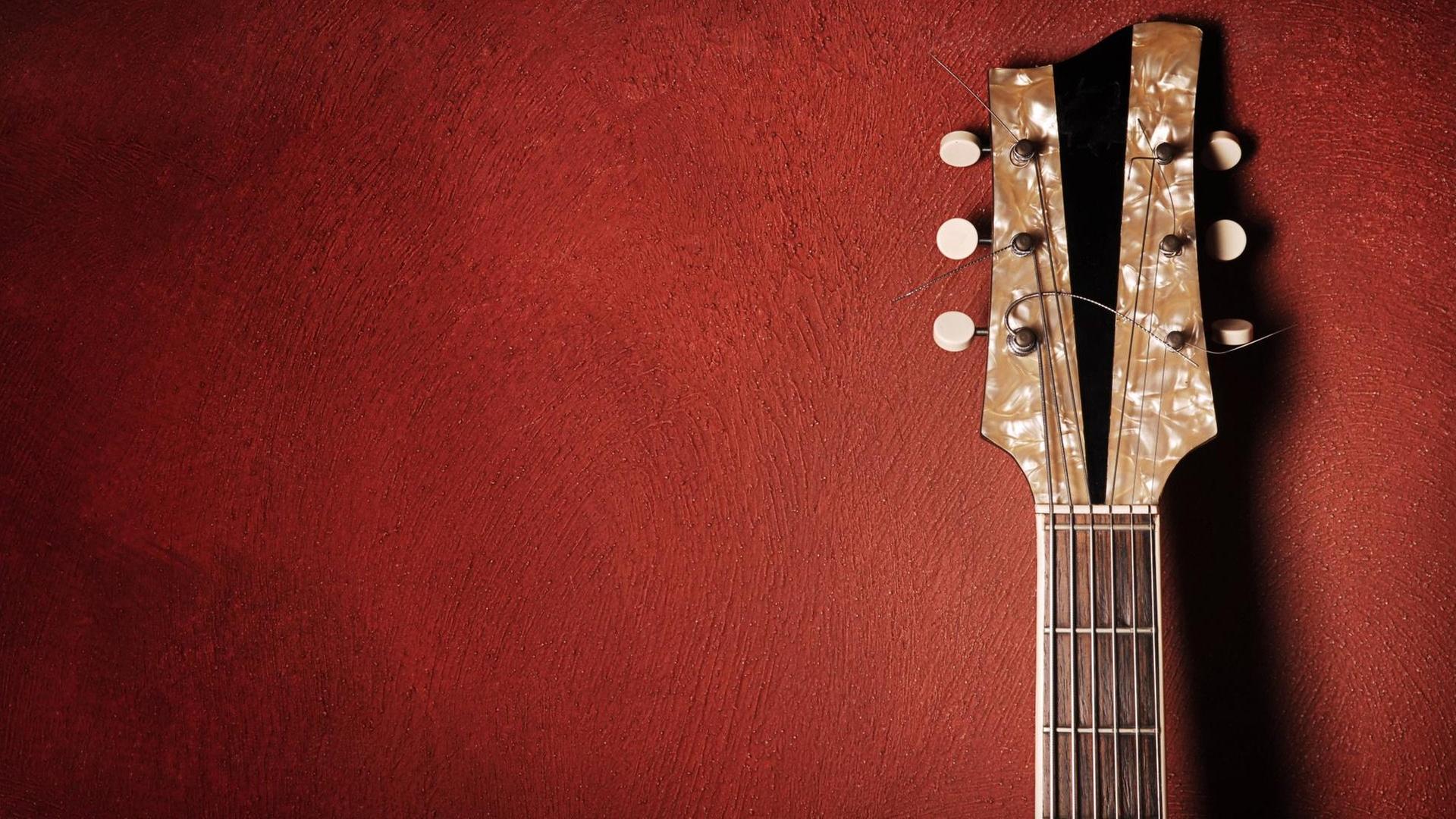 Gitarre lehnt gegen eine rote Wand Gitarre lehnt gegen eine rote Wand