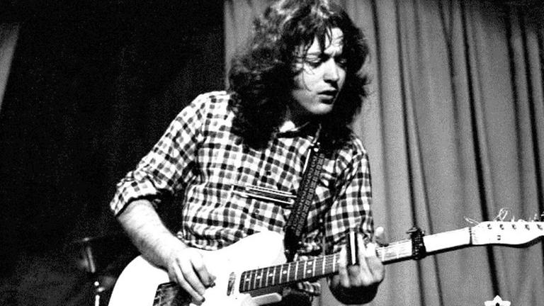 Ein Mann steht auf einer Bühne und spielt Gitarre Ein Mann steht auf einer Bühne und spielt Gitarre
