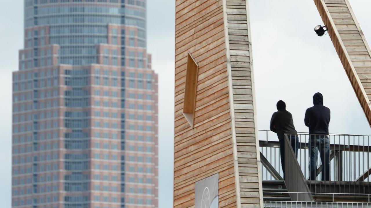 Zwei Männer stehen am 23.03.2014 auf einem hölzernen Aussichtsturm im Europaviertel in Frankfurt am Main (Hessen) in Sichtweite des Messeturms. Zwei Männer stehen am 23.03.2014 auf einem hölzernen Aussichtsturm im Europaviertel in Frankfurt am Main (Hessen) in Sichtweite des Messeturms.