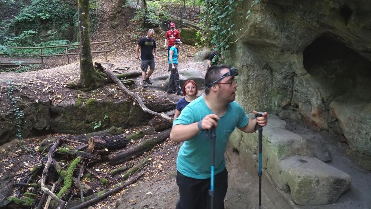 Eine Wandergruppe läuft an einem Felsvorsprung bergauf. Eine Wandergruppe läuft an einem Felsvorsprung bergauf.