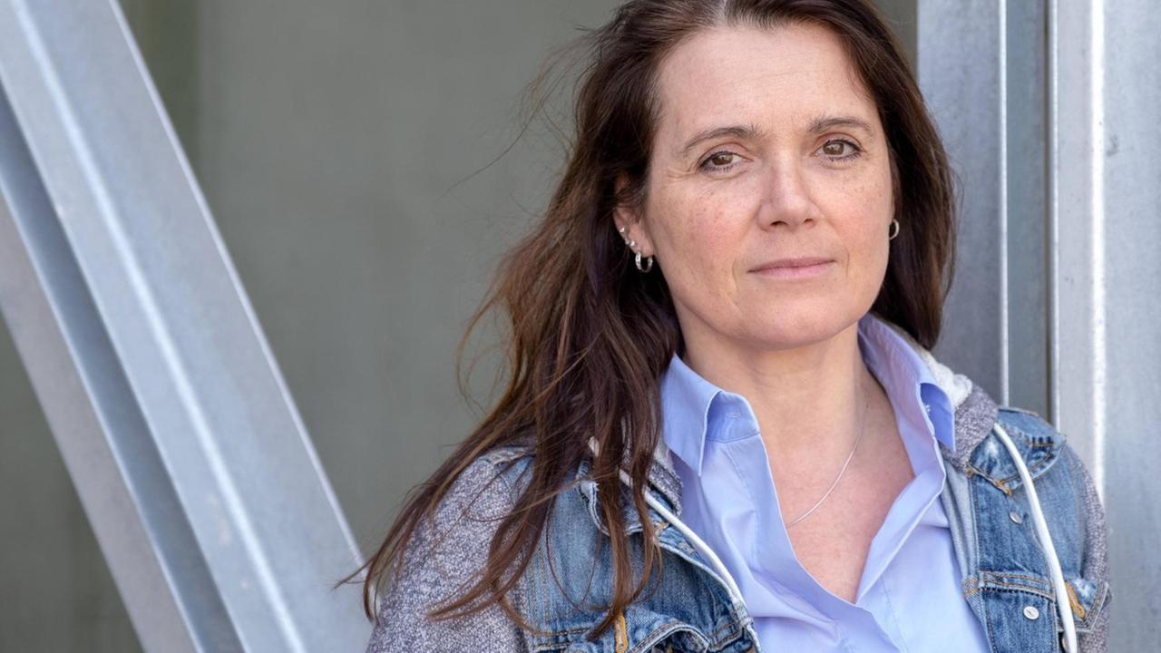 Barbara Junge steht in legerer Kleidung und mit ernstem Blick vor einer Metallkonstruktion. Barbara Junge steht in legerer Kleidung und mit ernstem Blick vor einer Metallkonstruktion.
