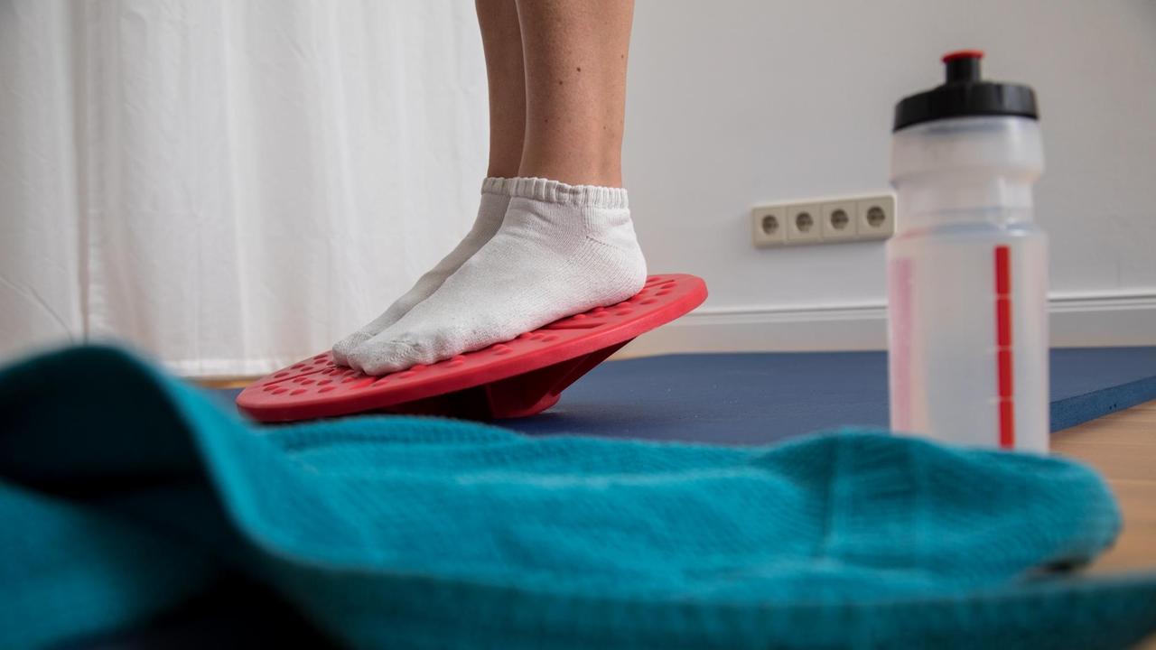 Eine Frau macht zuhause Gleichgewichtsübungen auf dem Balance-Board. Eine Frau macht zuhause Gleichgewichtsübungen auf dem Balance-Board.