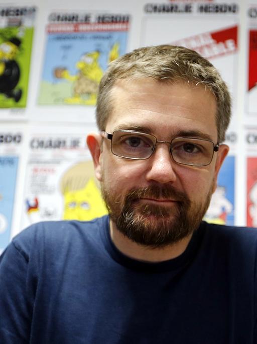 Der Karikaturist und Journalist Stéphane Charbonnier, genannt "Charb", vor einer Auswahl von Karikaturen.