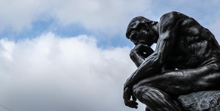 Die Plastik "Der Denker" ("Le Penseur") des Bildhauers Auguste Rodin vor wolkenverhangenen Himmel