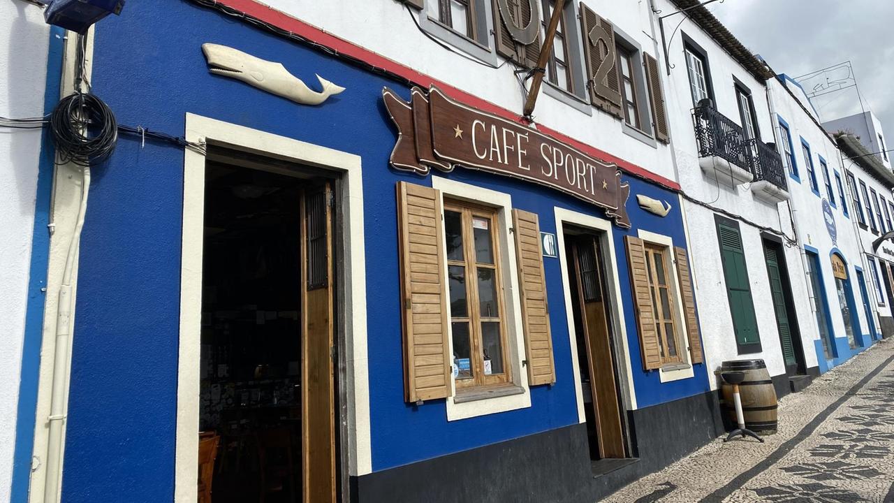 Ein blau-weiß gestrichenes Gebäude am Ende einer Reihe von Gebäuden von außen. Ein blau-weiß gestrichenes Gebäude am Ende einer Reihe von Gebäuden von außen.