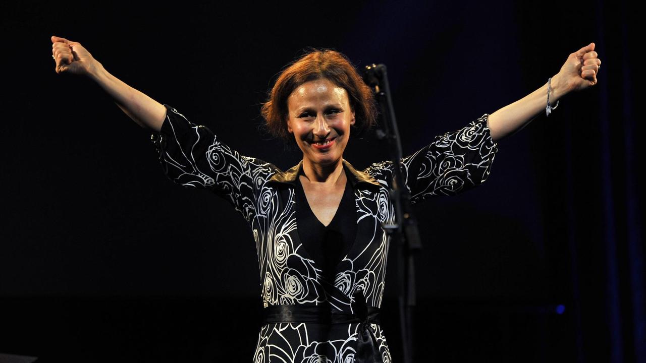 Etta Scollo begrüßt bei einem Live-Auftritt ihr Publikum mit einer herzlichen Geste. Etta Scollo begrüßt bei einem Live-Auftritt ihr Publikum mit einer herzlichen Geste.