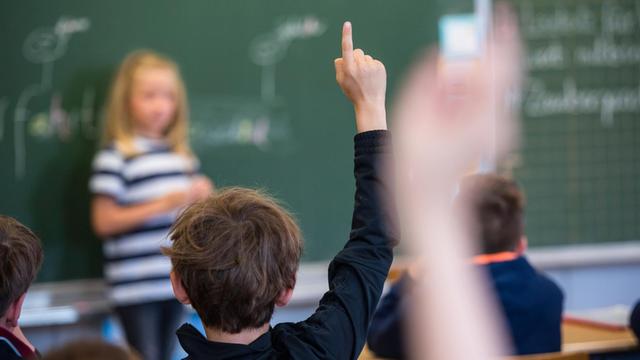 Schüler einer 3. Klasse im hessischen Bad Homburg melden sich im Unterricht, eine Schülerin steht vor der Tafel, aufgenommen 2018