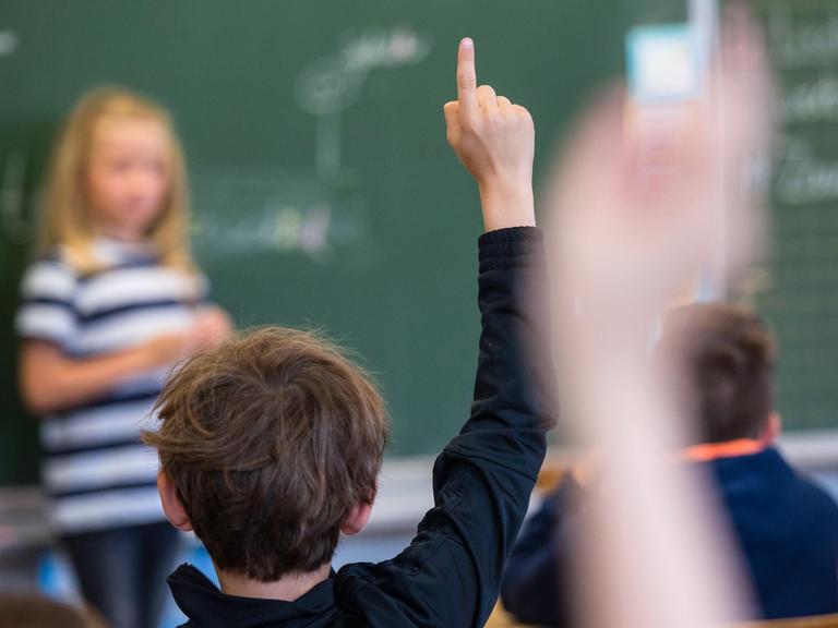 Schüler einer 3. Klasse im hessischen Bad Homburg melden sich im Unterricht, eine Schülerin steht vor der Tafel, aufgenommen 2018