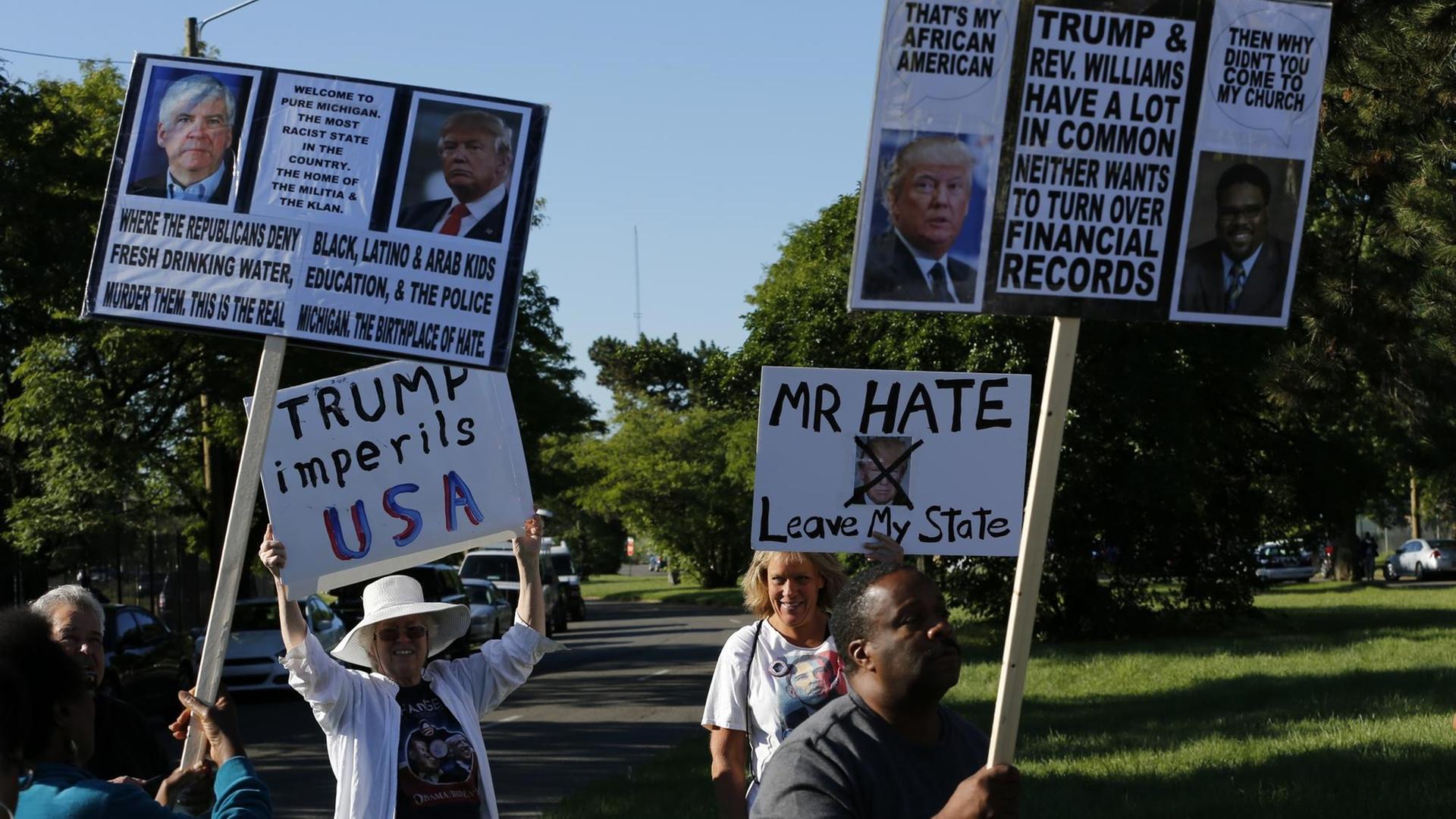 Demonstranten vor der Great Faith Ministries Kirchengemeinde in Detroit. Ihr Protest richtet sich gegen den republikanischen Präsidentschaftskandidaten Donald Trump, der am 3.9.2016 in der Kirche spricht. Er verspricht den Afroamerikanern mehr Wohlstand und Jobs. Demonstranten vor der Great Faith Ministries Kirchengemeinde in Detroit. Ihr Protest richtet sich gegen den republikanischen Präsidentschaftskandidaten Donald Trump, der am 3.9.2016 in der Kirche spricht. Er verspricht den Afroamerikanern mehr Wohlstand und Jobs.