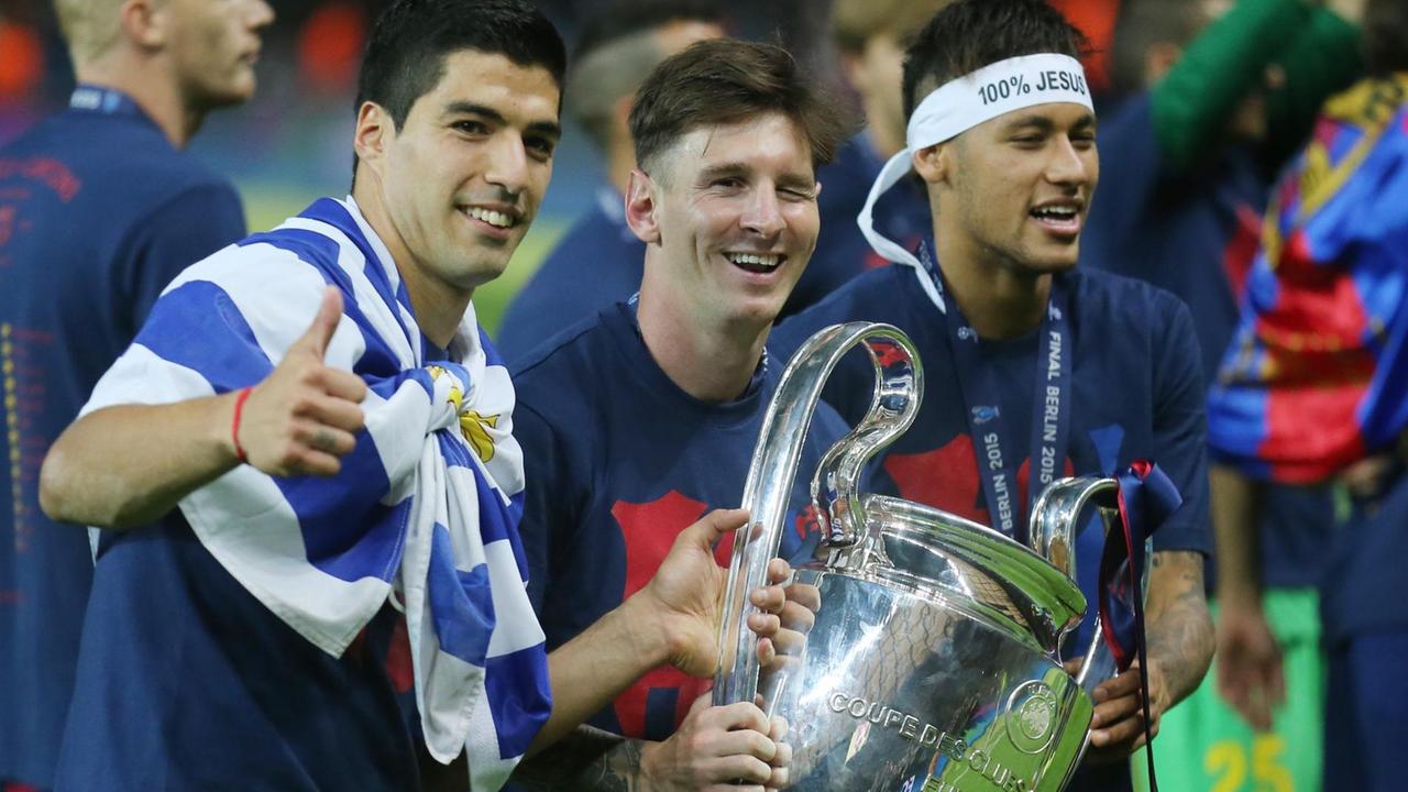 Die Barcelona-Spieler Suarez, Messi und Neymar freuen sich im Berliner Olympia-Stadion über den Gewinn der Champions League. Messi hält den Pokal in den Händen und blinzelt in die Kamera.