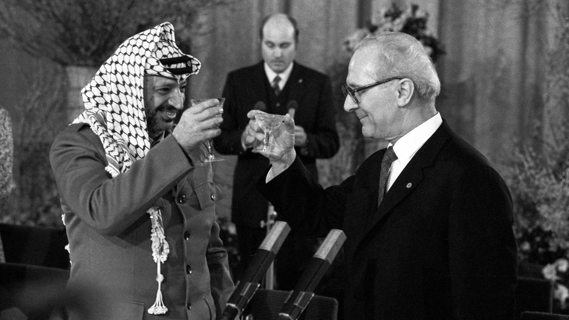 Staatsratsvorsitzender Erich Honecker und Yasser Arafat heben ihre Gläser zum Antoßen an.