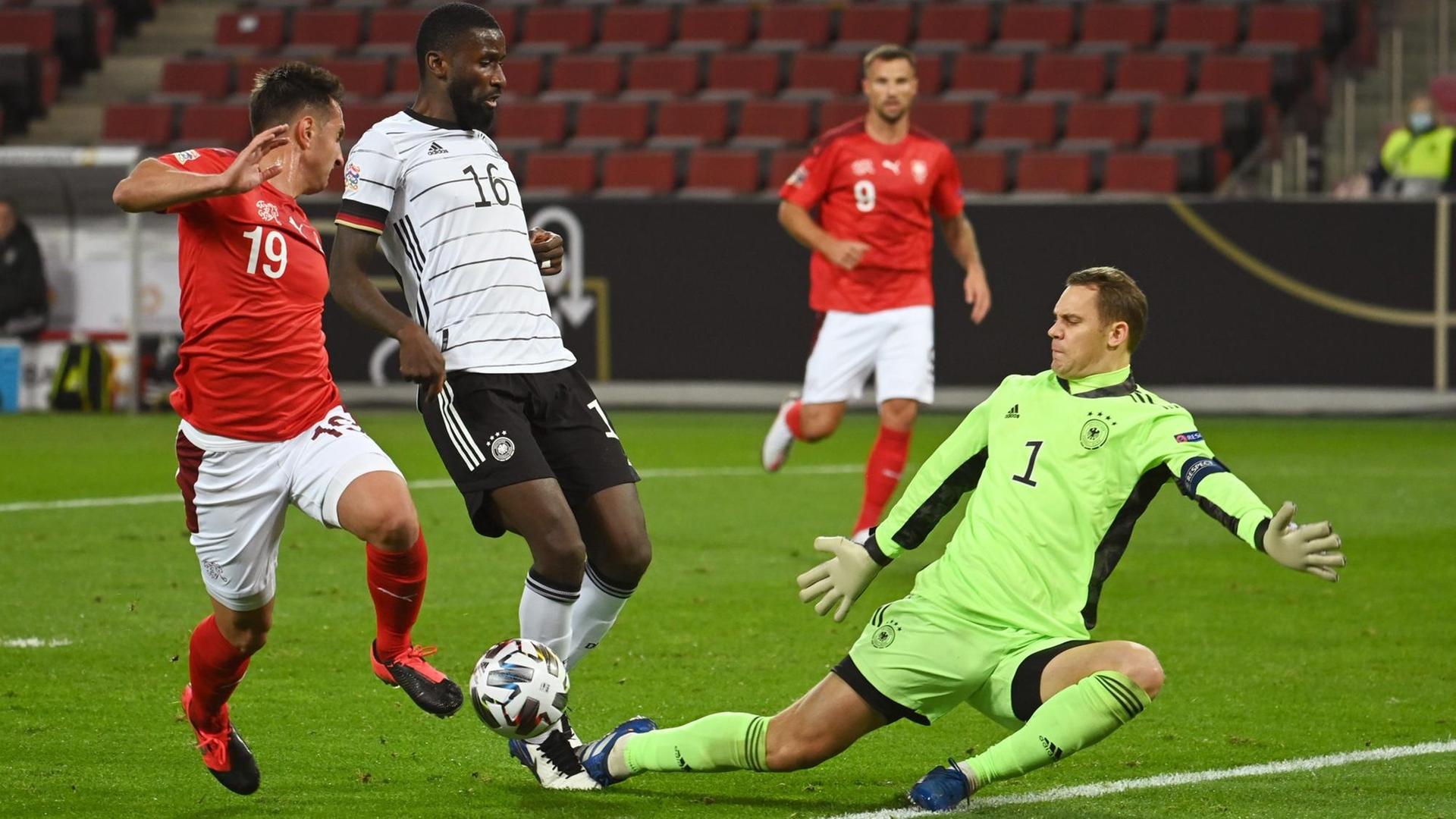 Deutschlands Torwart Manuel Neuer (r) und Antonio Rüdiger (2.vl) kämpfen mit dem Schweizer Mario Gavranovic um den Ball. Deutschlands Torwart Manuel Neuer (r) und Antonio Rüdiger (2.vl) kämpfen mit dem Schweizer Mario Gavranovic um den Ball.