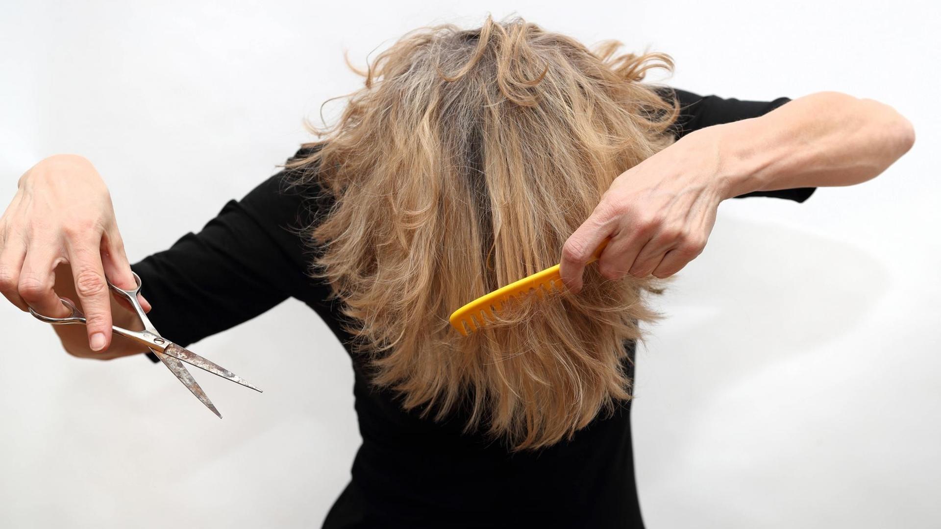Symbolfoto zeigt ein Person, die sich umständlich versucht selber die Haare zu schneiden. Symbolfoto zeigt ein Person, die sich umständlich versucht selber die Haare zu schneiden.