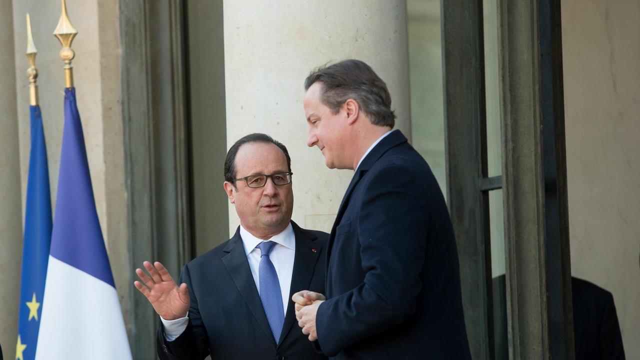 Frankreichs Präsident Hollande und der britische Premier Cameron stehen neben Flaggen der EU und Frankreichs und diskutieren.
